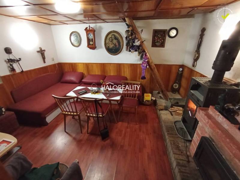 Rusztikus faház, fából készült mennyezet, kandalló, kényelmes ülőgarnitúra, hagyományos belső tér, kellemes légkör.