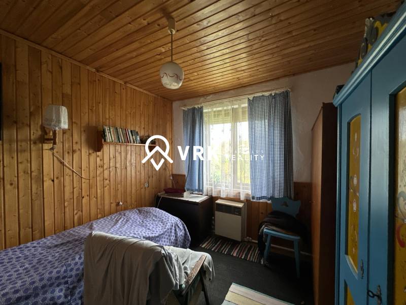 Egy szoba családi házban, fa burkolatú falakkal, kék szekrénnyel és ággyal.