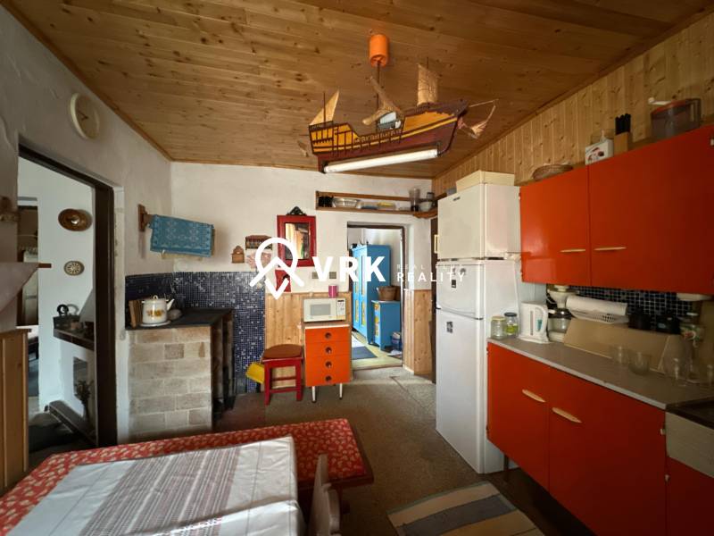 Rusztikus konyha színes szekrényekkel és fa mennyezettel egy családi házban.