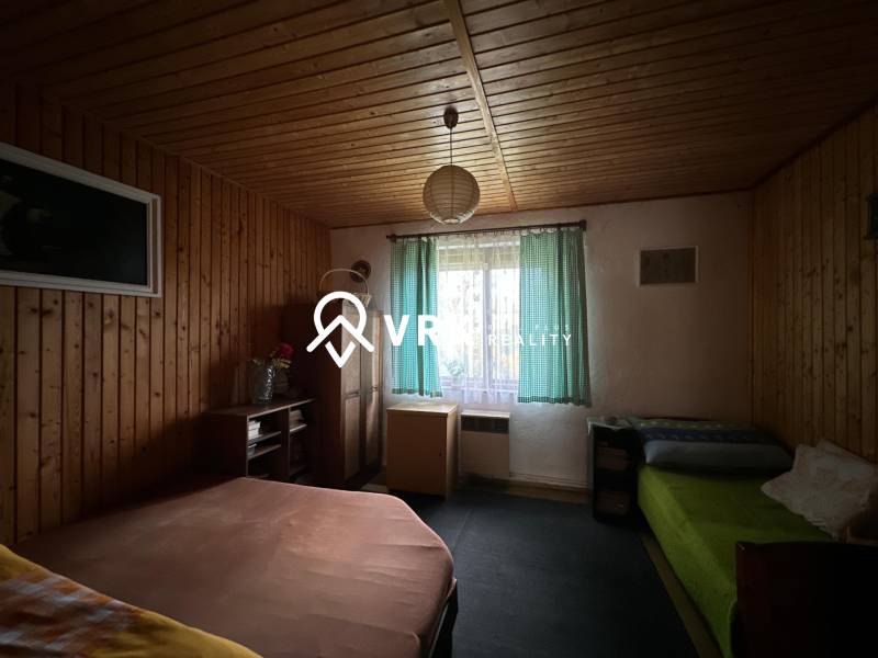 Szoba fa burkolattal és ágyakkal egy családi házban.