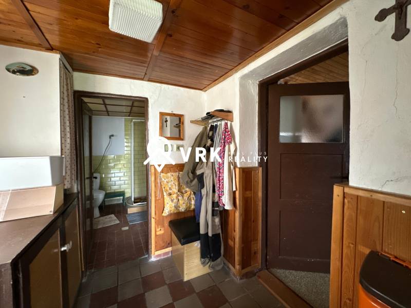 Családi ház belső tere fürdőszobai bejárattal és ruhafogasokkal.