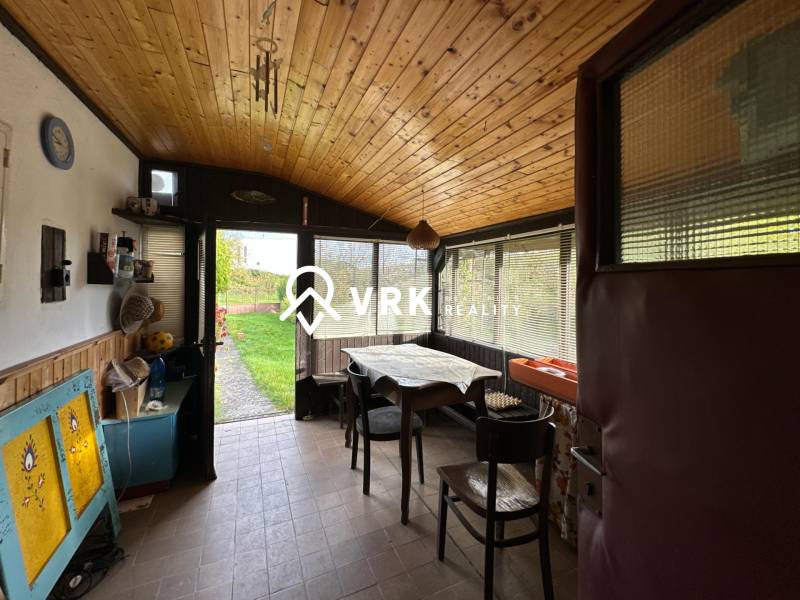 Családi ház belső tere fa dekorációjú padlóval, étkezőasztallal és kilátással a kertre.