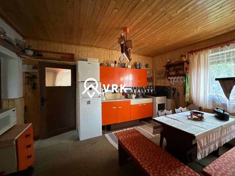 Konyha családi házban antik bútorokkal, rusztikus fal, nagy ablak.