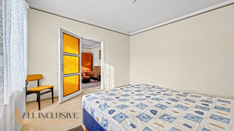 Hálószoba családi házban ággyal, székkel és narancssárga üveges ajtóval.