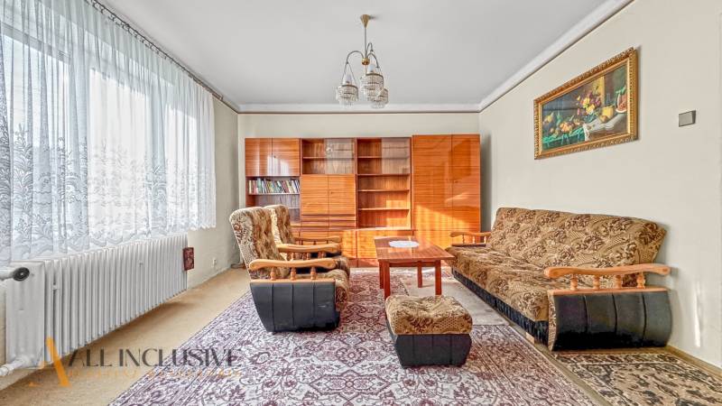 Nappali családi házban szőnyegekkel, bútorokkal és fotelekkel, dekoratív képpel.