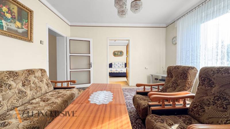 Családi ház nappalival, virágos bútorokkal, dohányzóasztallal és képpel a falon.