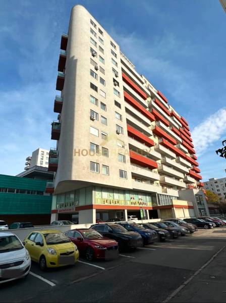 Lakóház a pozsonyi Martinčekova utcában parkolóval és erkélyekkel, napos égbolt.