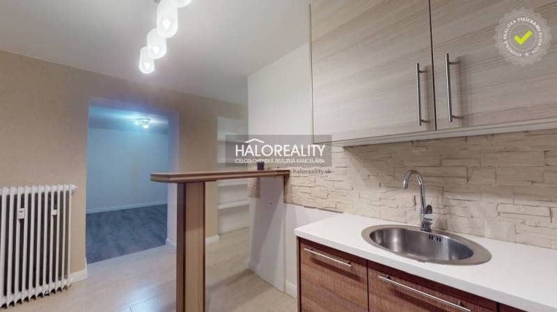 Kétszobás lakás konyhája fa dekor padlóval és bárpulttal.