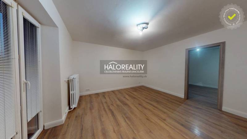 Tágas szoba egy kétszobás lakásban fa dekorációjú padlóval és radiátorral.