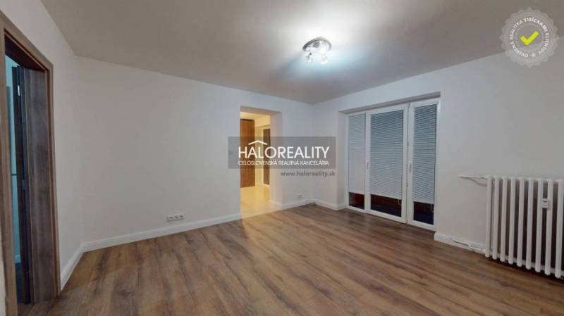 Nappali egy kétszobás lakásban fa dekor padlóval és francia ablakkal.