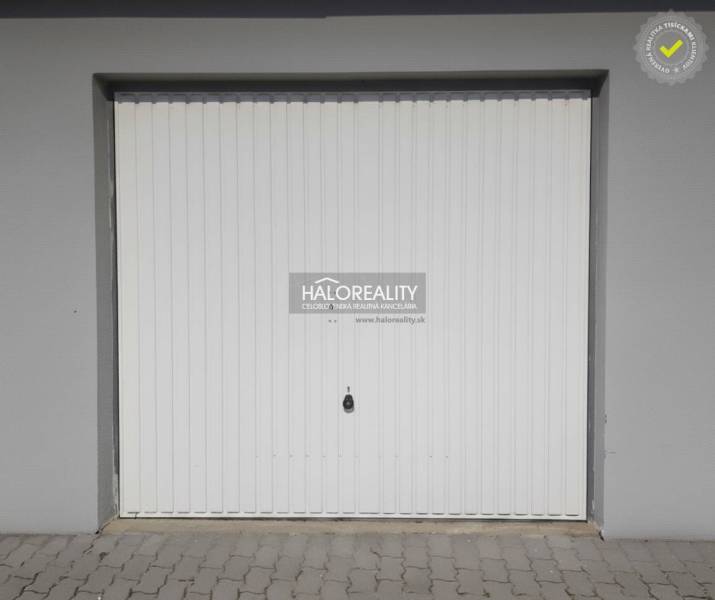 Fehér garázskapu Borcsicén térkövezettel.