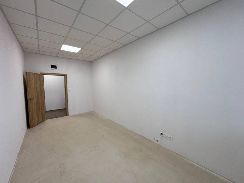 Iroda belső tér fehér falakkal, álmennyezettel és nyitott ajtókkal.