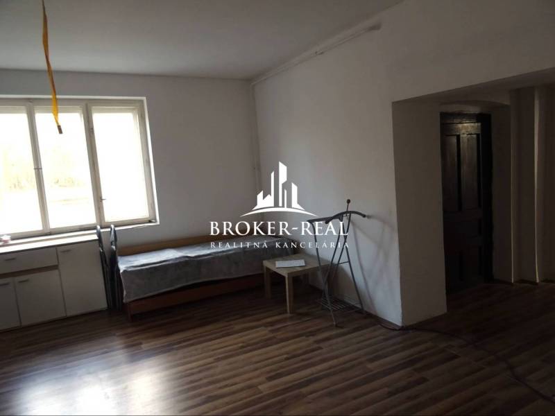 Családi ház fa mintázatú padlóval, ablakkal és bútorokkal.