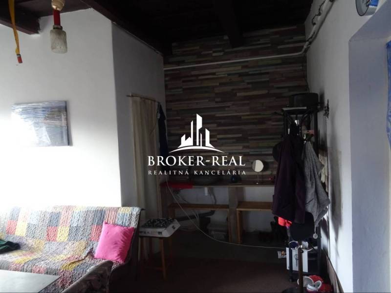 Családi ház belső tere kanapéval és fogassal, háttérben burkolt fal.