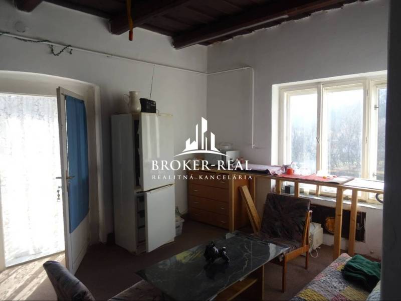 Egy szoba családi házban, világos asztallal az ablaknál, fotellel és étkezőasztallal.