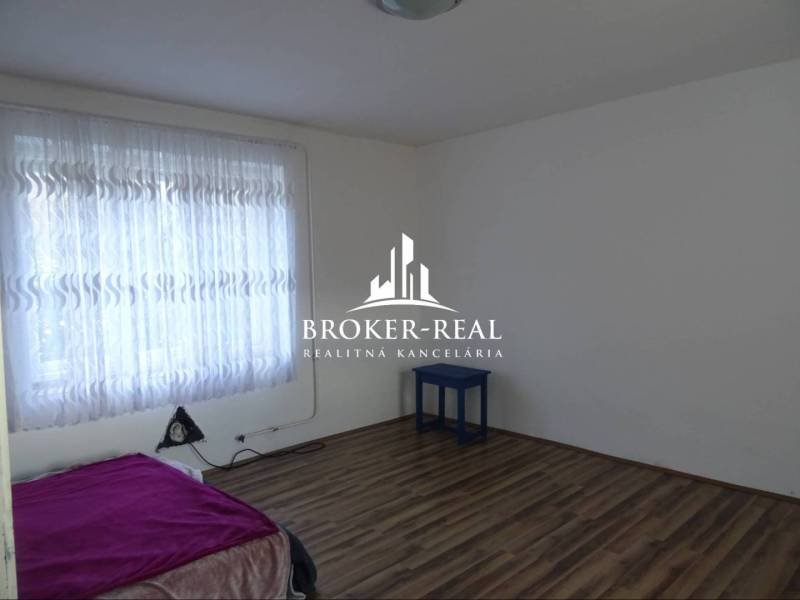 Szoba ággyal, függönyökkel és fa dekorációjú padlóval egy családi házban.