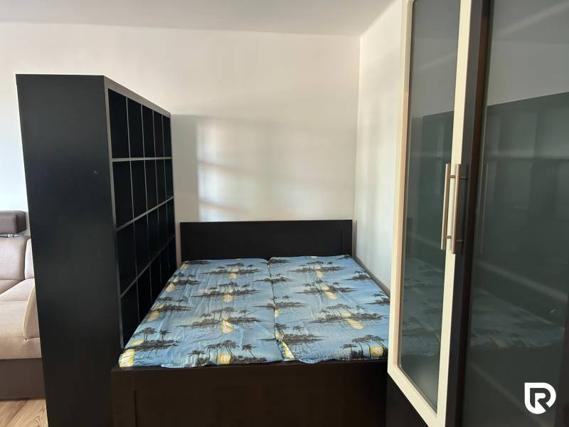 Hálószoba egy egyszobás lakásban ággyal és tárolószekrényekkel.