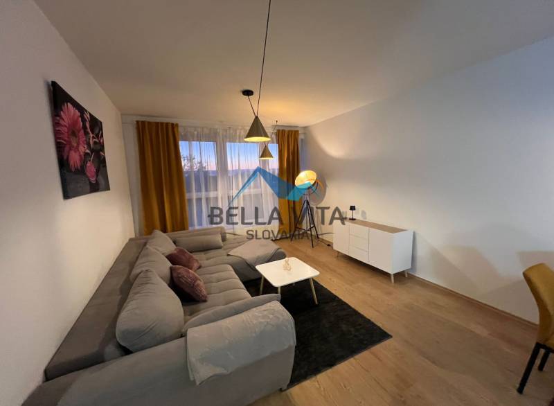 Nappali egy kétszobás lakásban kanapéval és fa dekorációjú padlóval.