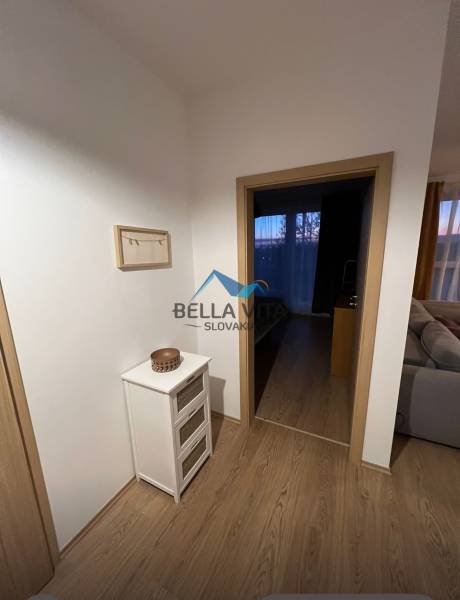 2 szobás lakás belső tere fa mintázatú padlóval, világos bútorokkal és dekorációkkal.