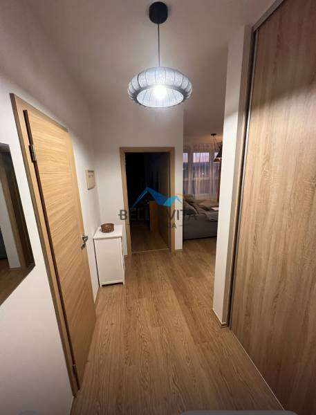 Folyosó egy kétszobás lakásban fa dekor padlóval és egyszerű világítással.