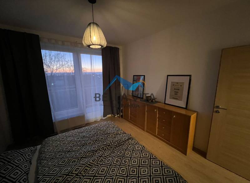 Hálószoba komóddal és lámpával, fa dekoros padlóval egy kétszobás lakásban.