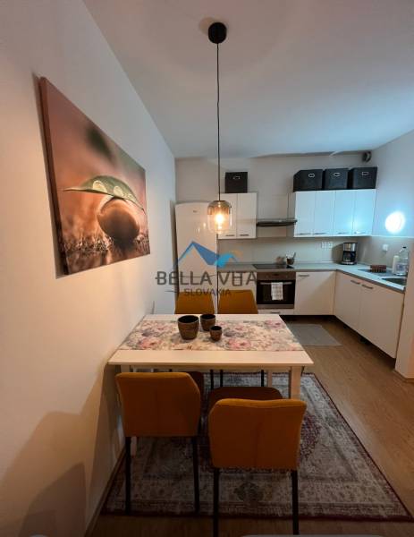 A kétszobás lakás konyhája étkezőasztallal, sárga székekkel és fa dekorú padlóval.