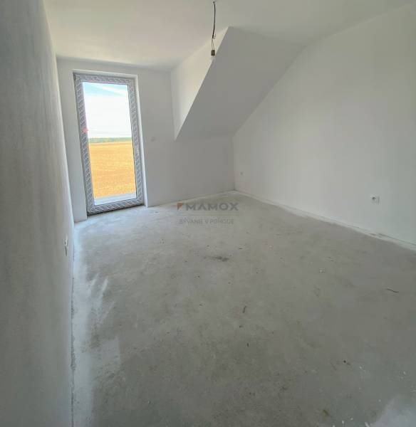 Szoba családi házban üvegezett ajtókkal és ferde mennyezettel, üres padló.