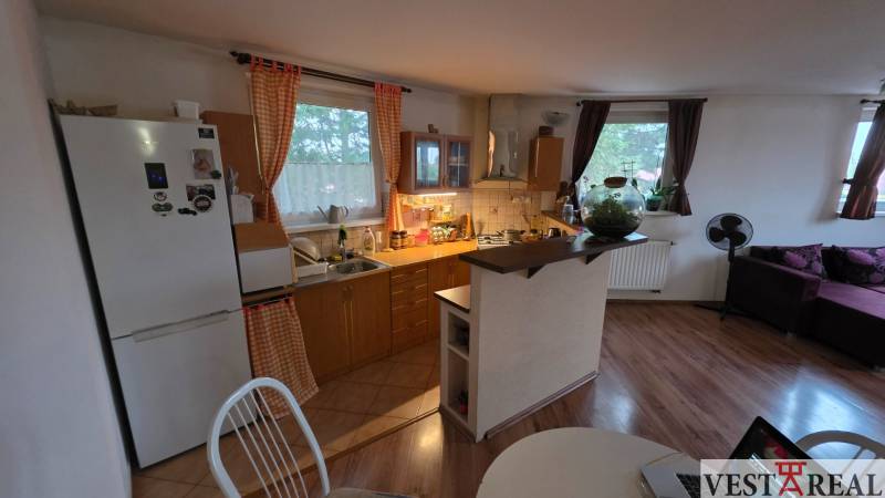 Konyha egy háromszobás lakásban fa dekor padlóval és étkezőasztallal.