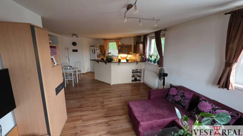 Nappali konyhával egy háromszobás lakásban, fa dekor padlóval.