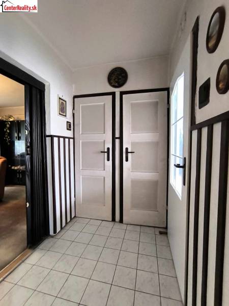 Családi ház belső tere fehér ajtókkal, csempével és sötét falburkolattal.