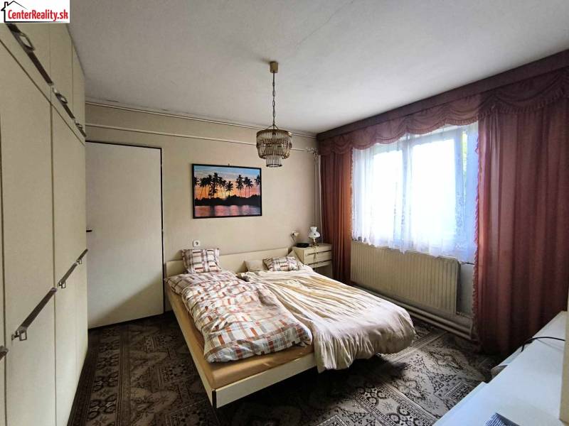 Hálószoba családi házban ággyal, szekrénnyel és képpel a falon.