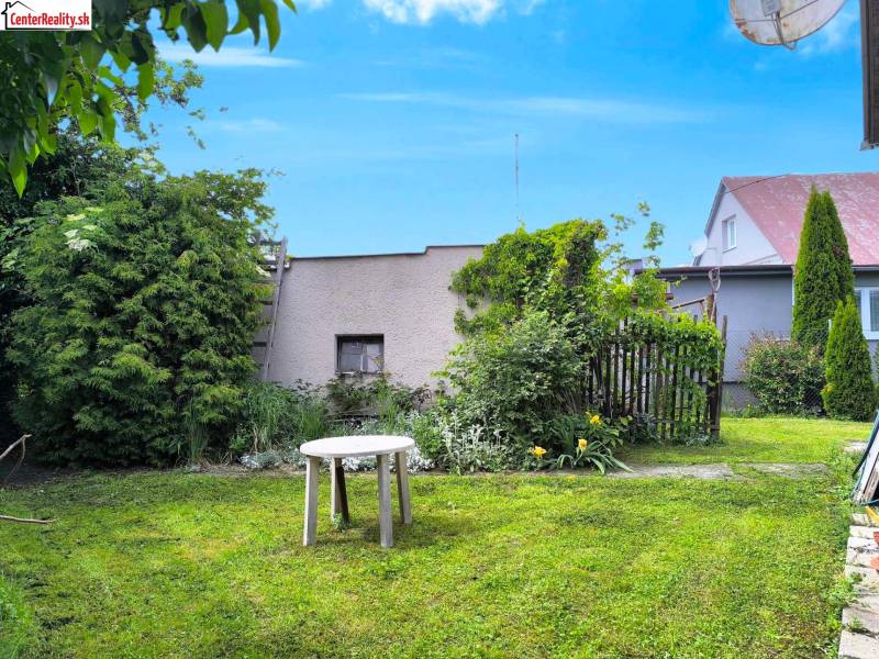 Családi ház kertje Nyitrán gyepesítéssel, asztallal és díszcserjékkel.