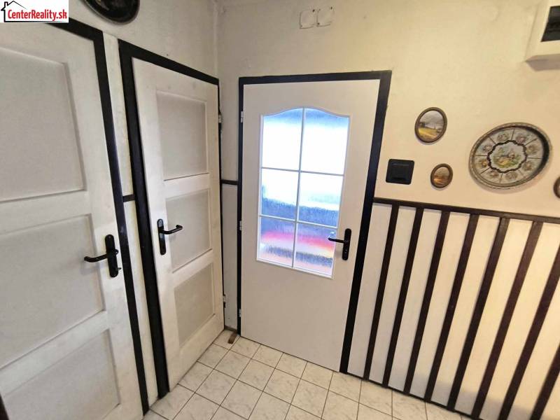 Családi ház belső tere fehér ajtókkal, faldekorációkkal és padlólapokkal.