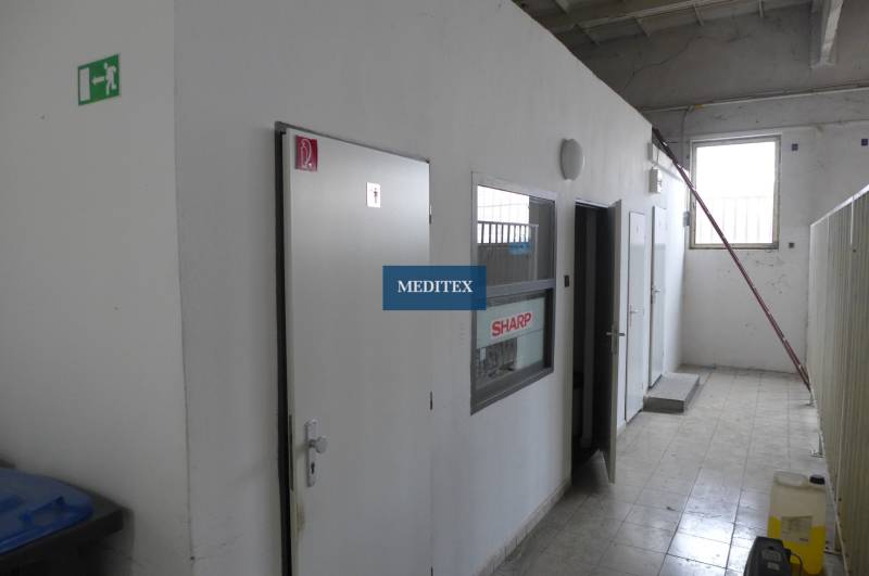 Belső tér fehér ajtókkal és szürke falakkal raktár- és csarnokhelyiségekben.