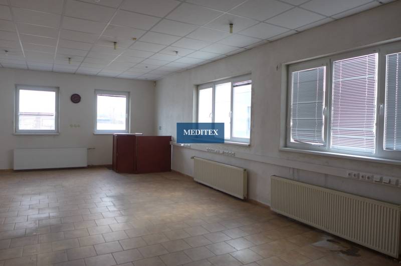 Irodai helyiség raktárakban és csarnokokban világos csempével és nagy ablakokkal.