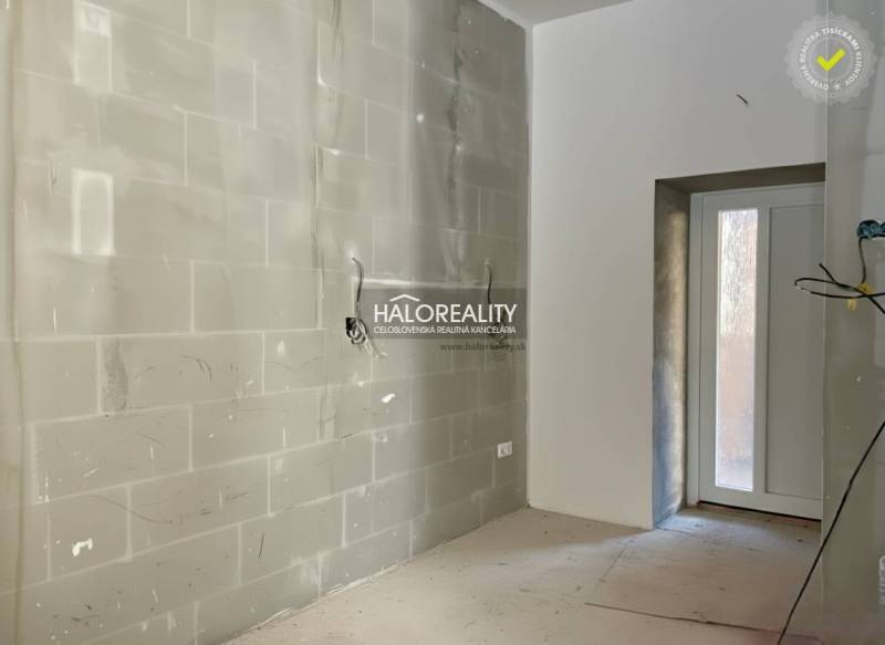 Világos szoba befejezetlen falakkal egy családi házban, bejárati ajtóval.