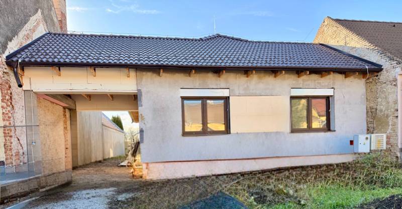 Családi ház Cíferen vakolatlan homlokzattal és barna tetőfedéssel.