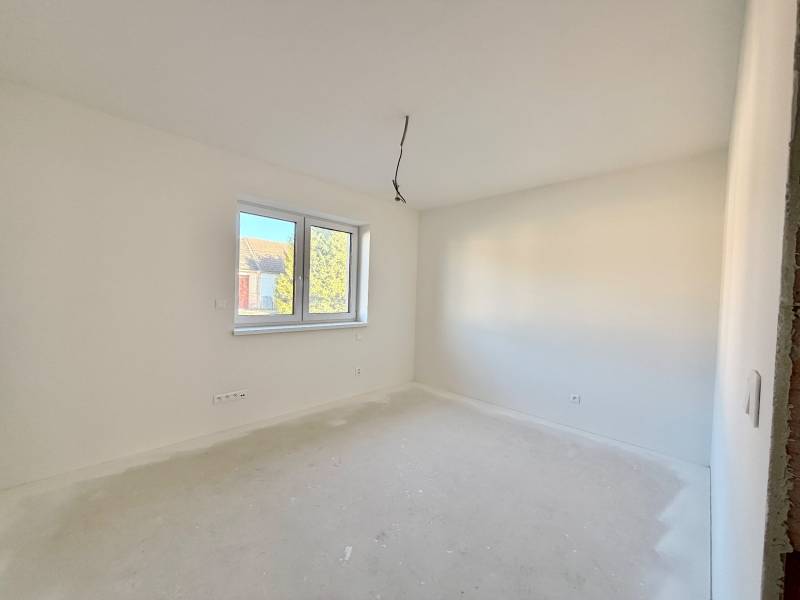 Tágas, világos szoba egy családi házban, dupla ablakkal és fehér falakkal.