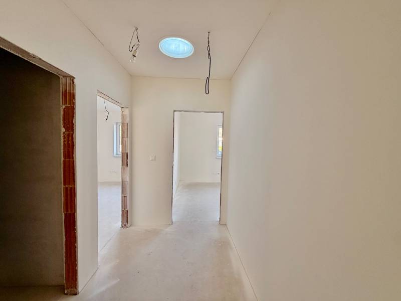 A családi ház folyosója ideiglenes világítással és betonpadlóval.