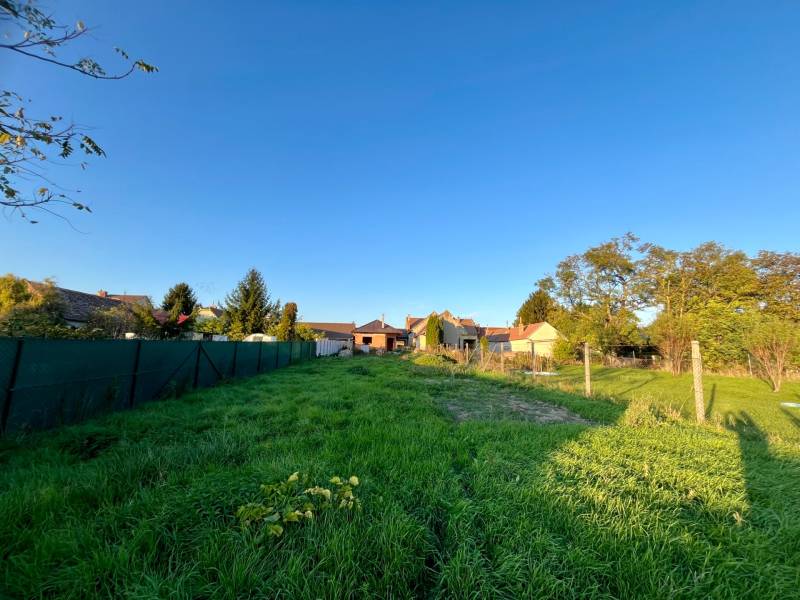 Fűvel borított és kerítéssel körülvett telek Cíferen, családi házak közelében.