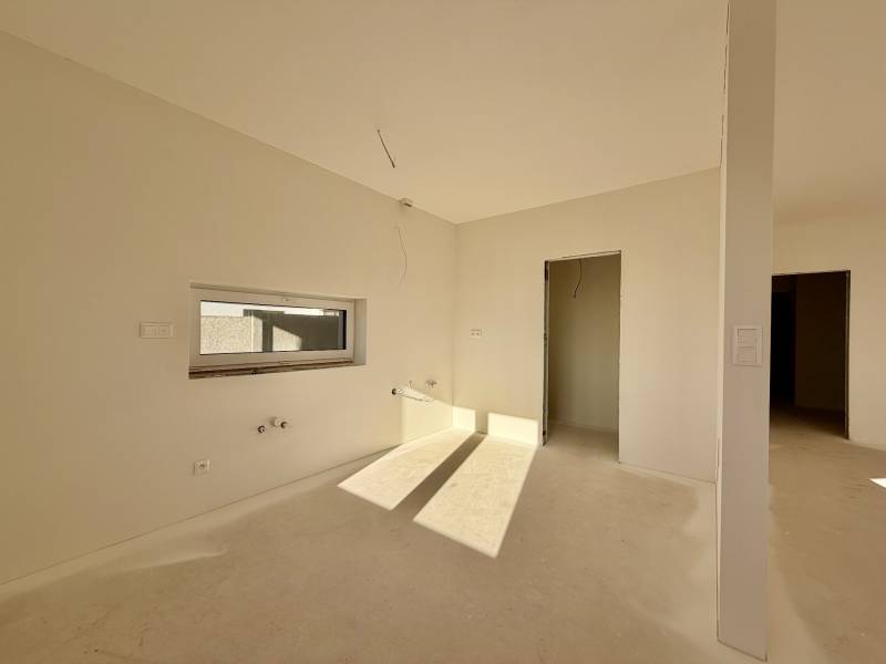 Tágas, nem berendezett szoba egy családi házban, ablakkal és ajtóval, padló nélkül.