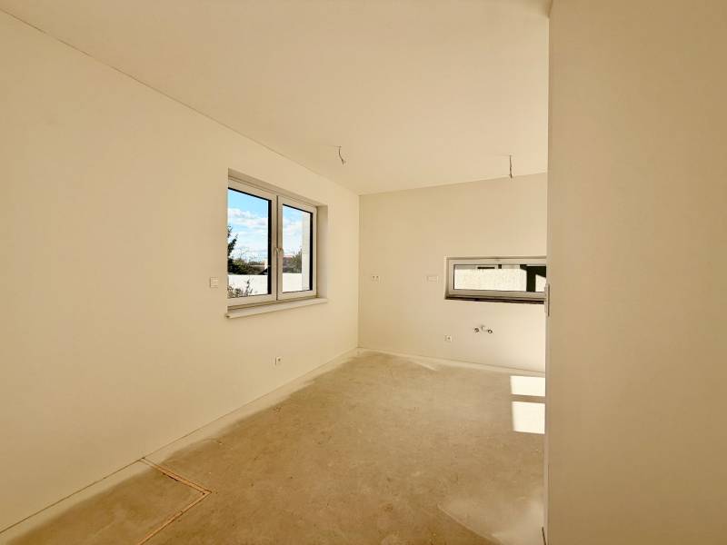 Üres szoba dupla ablakkal és betonpadlóval egy családi házban.