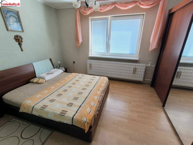 Hálószoba családi házban ággyal, szekrénnyel és fa dekoros padlóval.