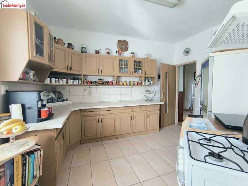 Konyha családi házban fa szekrényekkel és kerámia padlóval.