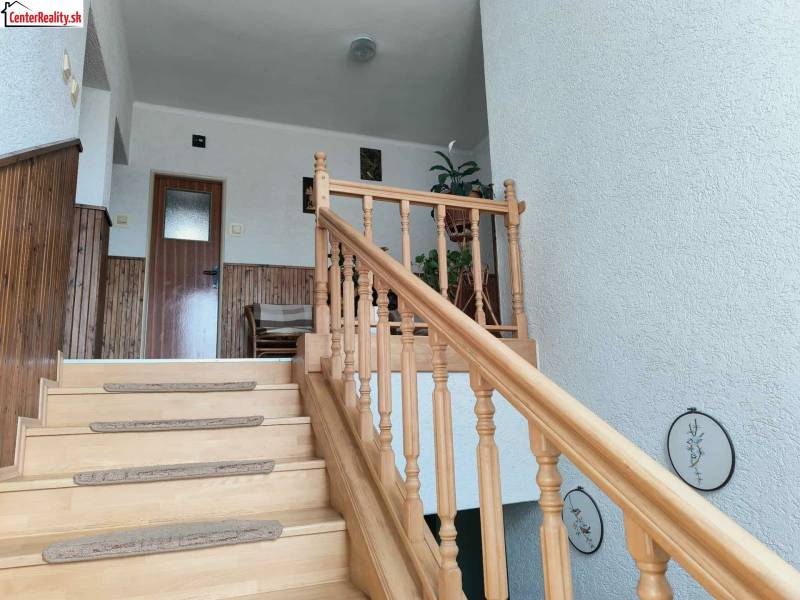 Családi ház fa lépcsővel, falburkolattal és dekorációval.