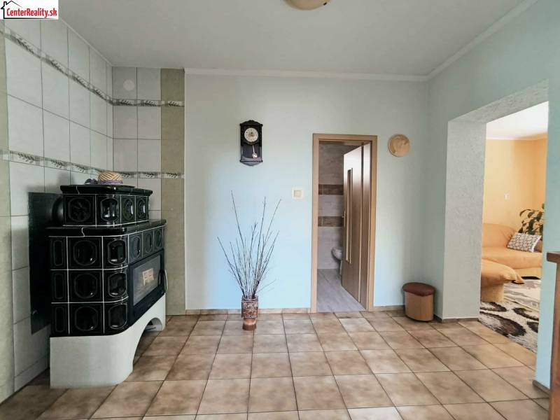 Családi ház belső tere zöld csempékkel, cserépkályhával és padlóburkolattal.