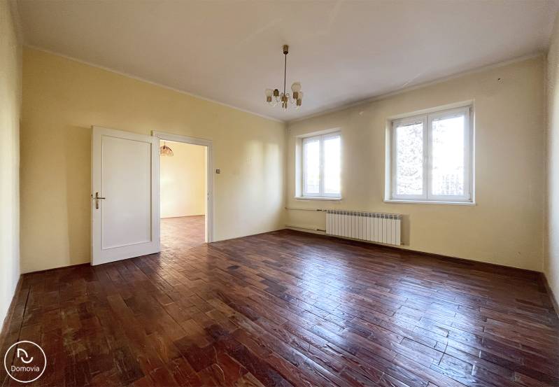 Tágas szoba fa mintás padlóval és két nagy ablakkal.