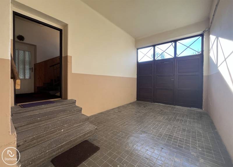 Előcsarnok garázsajtóval egy 5 vagy több szobás lakásban, a lépcsők a belső térbe vezetnek.