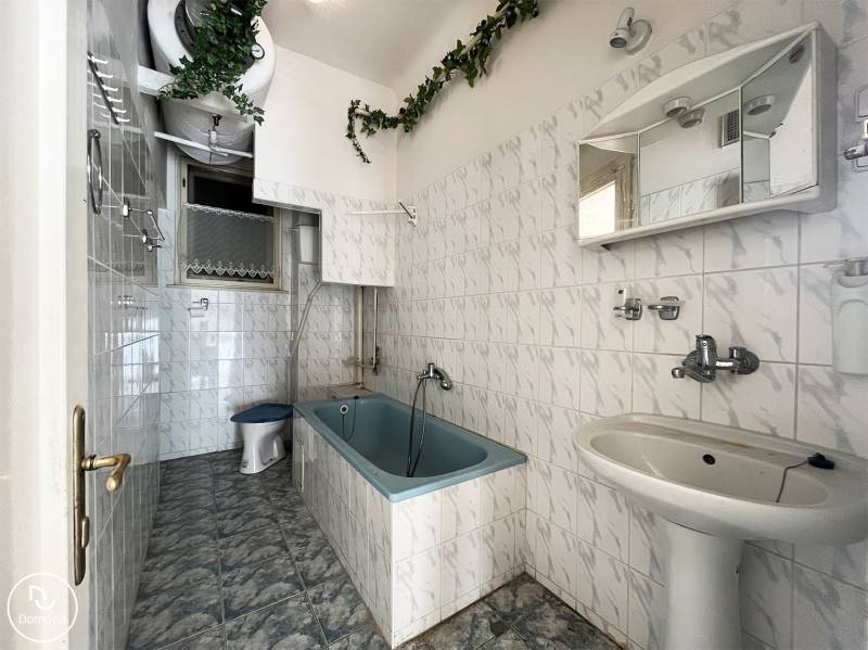 Fürdőszoba káddal, fehér csempékkel és zöld dekorációval egy öt vagy több szobás lakásban.