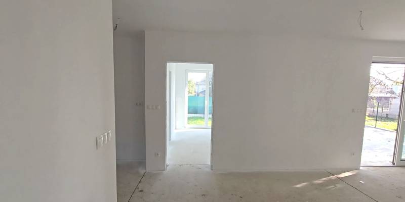 Családi ház világos szobával, fehér falakkal és nagy ablakokkal a kertre.